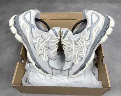 Pair of gray and white running shoes in a cardboard box on a gray background